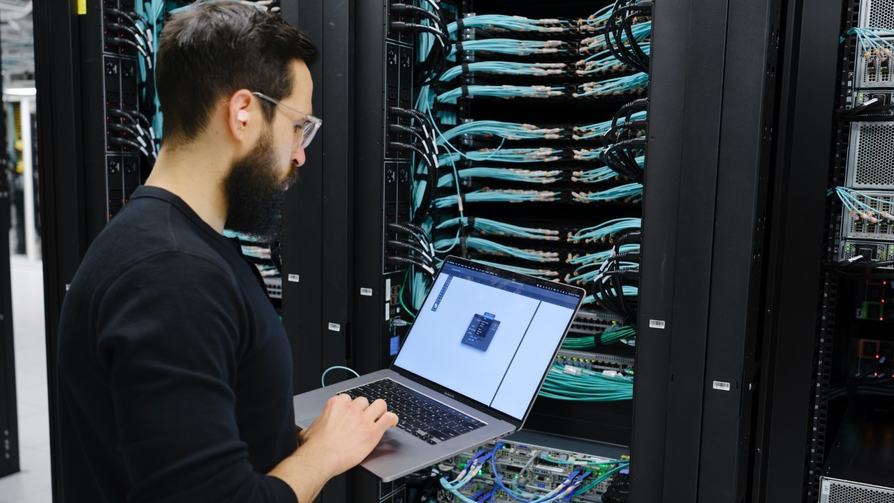 An up close image of two people working on a computer inside a data center.
